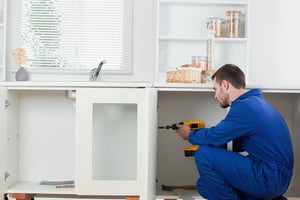 Good looking handyman fixing a door in a kitchen